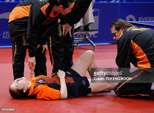 Trainer attends to the injured foot of Li Jie of the Netherlands during the women's quarter-final match at the World Team Table Tennis Championships...