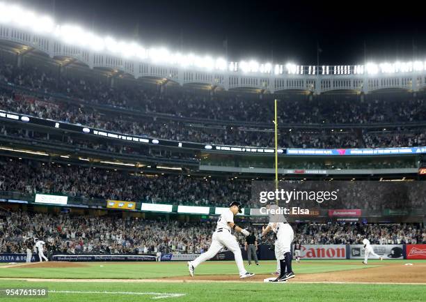 Gleyber Torres of the New York Yankees is congratulated by first base coach Reggie Willits after Torres hit a three run home run off pitcher Josh...