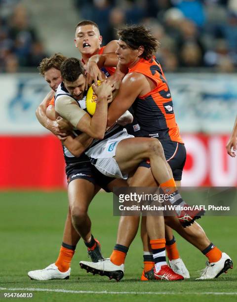 Sam Menegola of the Cats is tackled by Lachie Whitfield, Adam Tomlinson and Ryan Griffen of the Giants during the 2018 AFL round seven match between...