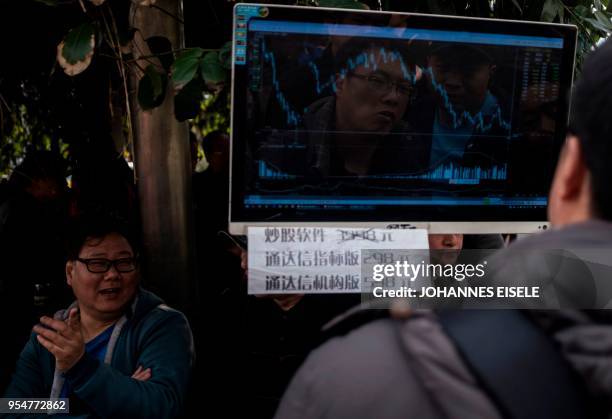 This picture taken on March 25, 2018 shows people looking at computer screens showing financial data at Shanghai's open-air investment bazaar. - For...