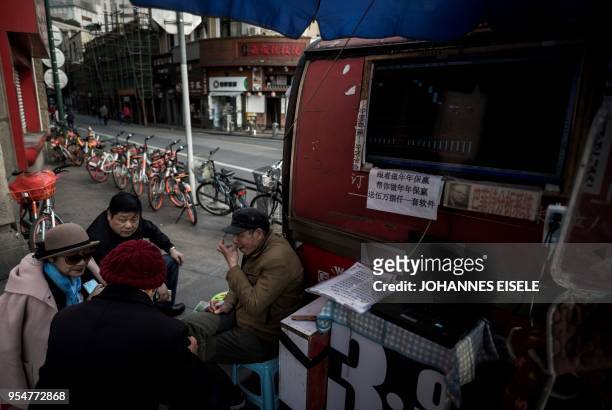 This picture taken on March 25, 2018 shows Shen Yuxi , who peddles stock analysis software, chatting with friends at Shanghai's open-air investment...