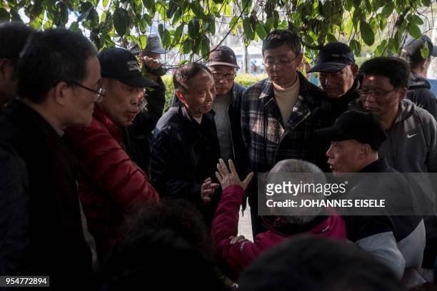 This picture taken on March 25, 2018 shows men discussing stock market movements at Shanghai's open-air investment bazaar. - For a quarter-century,...