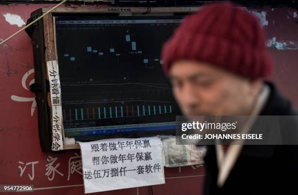This picture taken on March 25, 2018 shows Shen Yuxi , who peddles stock analysis software, next to the screen of his computer showing financial data...