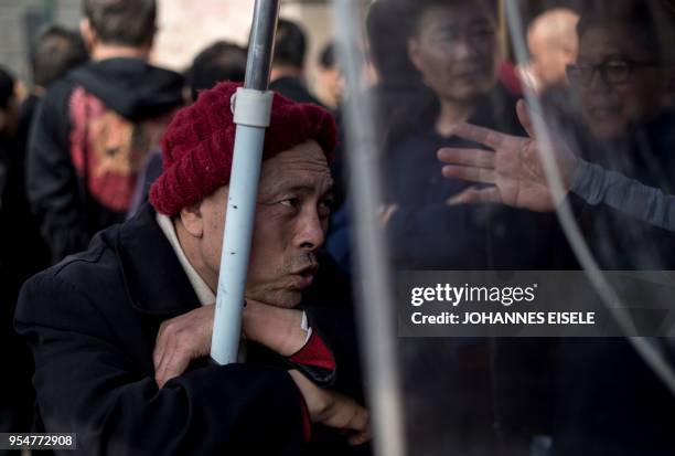 This picture taken on March 25, 2018 shows Shen Yuxi , who peddles stock analysis software, listening to people at Shanghai's open-air investment...