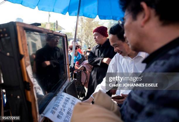 This picture taken on March 25, 2018 shows Shen Yuxi , who peddles stock analysis software, watching the screen of his computer showing financial...