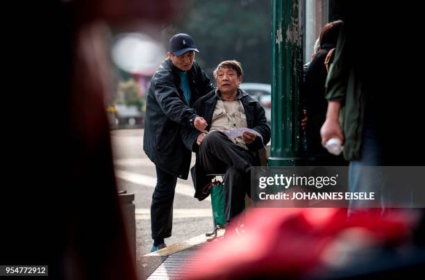 This picture taken on March 25, 2018 shows pensioners discussing stock movements at Shanghai's open-air investment bazaar. - For a quarter-century,...