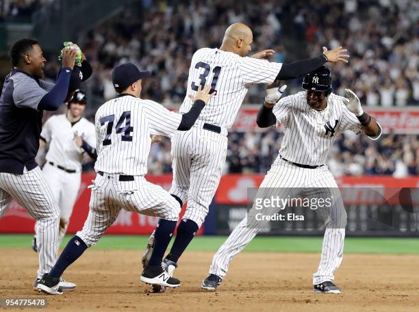 Miguel Andujar of the New York Yankees is chased by teammates Aaron Hicks and Ronald Torreyes of the New York Yankees after he drove in the game...
