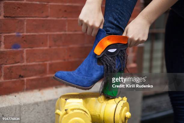 a woman is adjusting her boot in the street in new york - suede shoe stock pictures, royalty-free photos & images