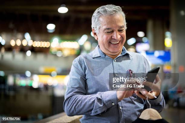 mature businessman using mobile phone at airport - information sign stock pictures, royalty-free photos & images
