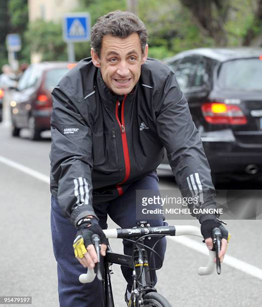 French president Nicolas Sarkozy leaves on his bike his wife, Carla Bruni-Sarkozy's residency on April 12, 2009 in the French city of Cavaliere,...