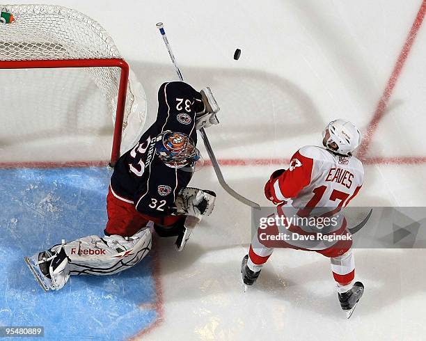 Mathieu Garon of the Columbus Blue Jackets blocks a high shot as Patrick Eaves of the Detroit Red Wings looks for the loose puck during a NHL game at...