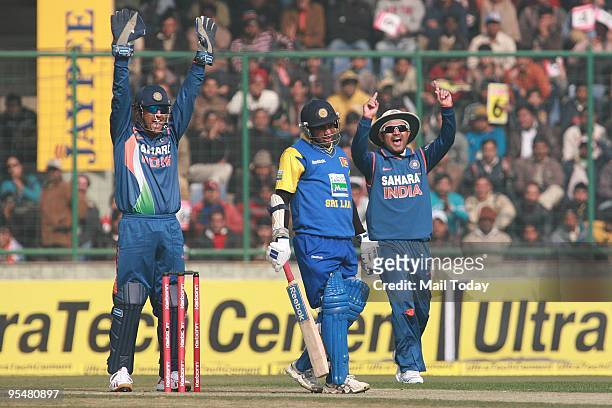 Indian cricket captain Mahendra Singh Dhoni, left, and teammate Virender Sehwag, center, celebrate after taking the wicket of Sri Lanka's Sanath...
