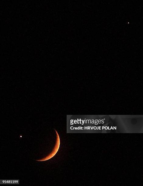 Picture taken from Croatian capital Zagreb, on December 01 shows a slender crescent moon, just 15-percent illuminated, as it appears in very close...