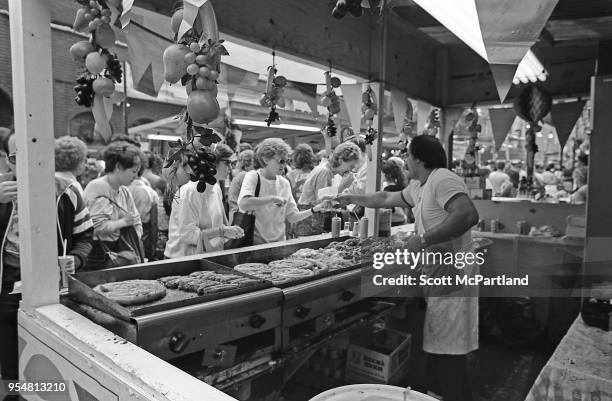 New York City - A food vendor grills up sausages and peppers, and serves customers at the annual Feast Of San Gennaro festival in Little Italy.