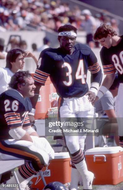 Runningback Walter Payton of the Chicago Bears stands next to the bench contemplating the plays that are happening on the field against the Tampa Bay...