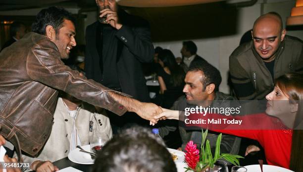 Cricketer Mahendra Singh Dhoni greets Arti Sehwag as Virender Sehwag looks on at a party in his honour, for his stupendous Test performance against...