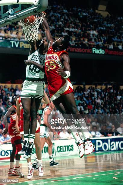 Robert Parish of the Boston Celtics dunks against Sly Williams of the Atlanta Hawks during a game played in 1984 at the Boston Garden in Boston,...