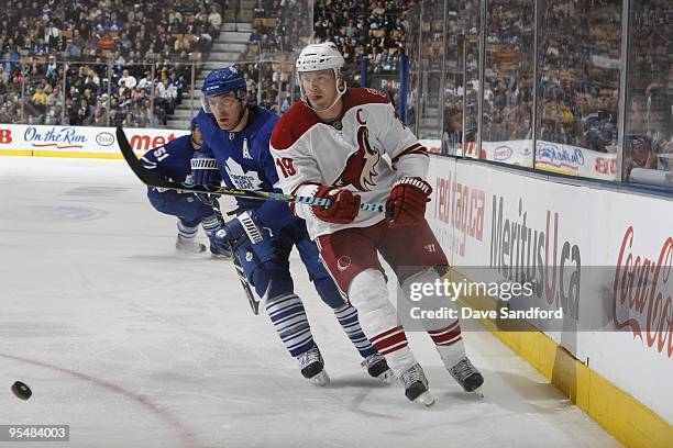 Shane Doan of the Phoenix Coyotes and Francois Beauchemin of the Toronto Maple Leafs skate after the puck during their NHL game at the Air Canada...