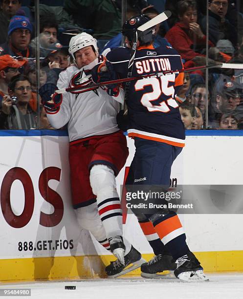 Umberger of the Columbus Blue Jackets is hit by Andy Sutton of the New York Islanders at the Nassau Coliseum on December 29, 2009 in Uniondale, New...