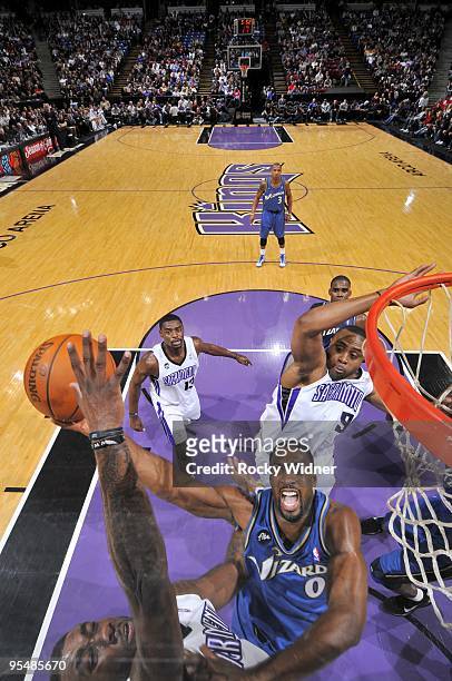 Gilbert Arenas of the Washington Wizards shoots a layup against Donte Greene and Kenny Thomas of the Sacramento Kings during the game at Arco Arena...