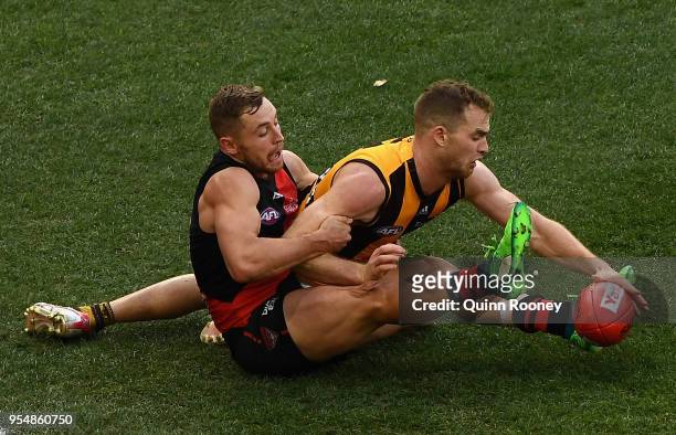 Devon Smith of the Bombers and Tom Mitchell of the Hawks compete for the ball during the round seven AFL match between the Essendon Bombers and the...