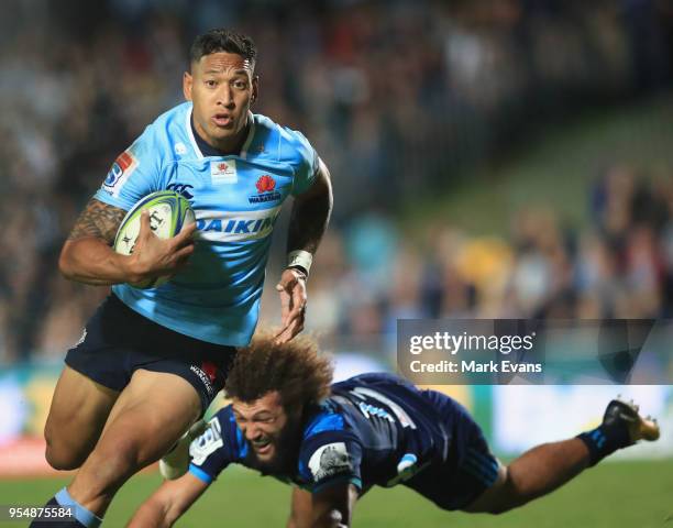 Israel Folau of the Waratahs breaks free from the tackle of Ross Wright of the Orbyn Leger of the Blues during the round 12 Super Rugby match between...