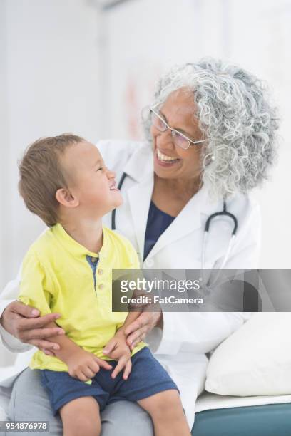 garçon enfant en bas âge-âge pose avec son médecin pour une photo sur la table d’examen - table dexamen médical photos et images de collection