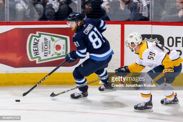 Kyle Connor of the Winnipeg Jets plays the puck around the boards as Roman Josi of the Nashville Predators gives chase during second period action in...