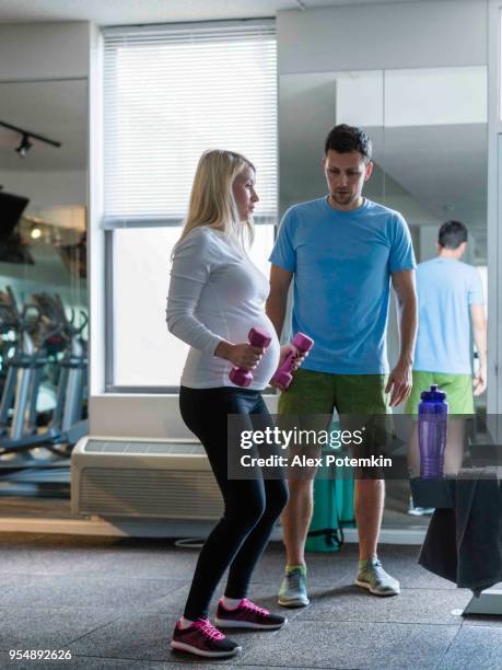 beautiful young white pregnant woman do fitness exercise in the gym with the personal trainer - alex potemkin or krakozawr latino fitness stock pictures, royalty-free photos & images