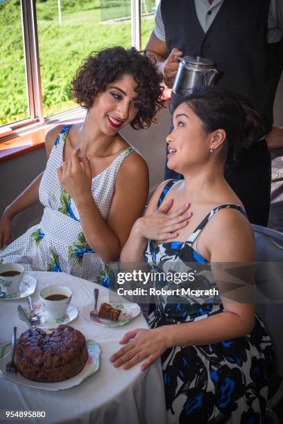 two women share a morning coffee, cake and stories in dining room. - robert mcgrath stock-fotos und bilder