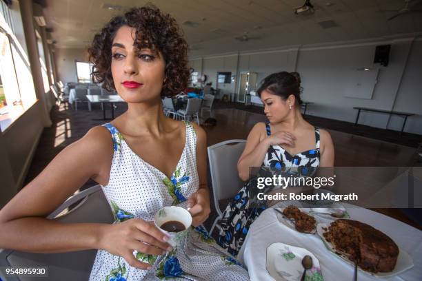 two smartly dress women, meet over coffee to discuss and compare their fashionable attire. the asian woman compares her attires unfavourably to her middle eastern companion, who confidently looks elsewhere. - 1961 stock pictures, royalty-free photos & images