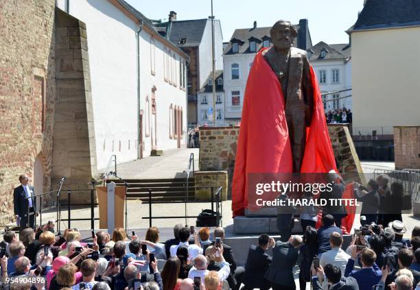 Visitors look on as a statue of German revolutionary thinker Karl Marx is being unveiled on May 5, 2018 in his native city Trier, southwestern...