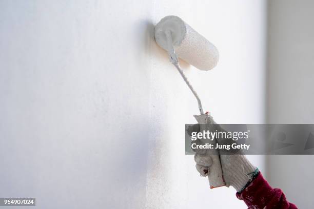 painter roller by construction worker in new cement wall - wall building feature stock pictures, royalty-free photos & images