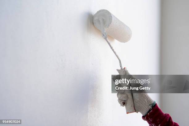 painter roller by construction worker in new cement wall - decorating loft imagens e fotografias de stock