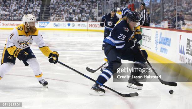 Patrik Laine of the Winnipeg Jets looks to move the puck under pressure from Ryan Ellis of the Nashville Predators in Game Four of the Western...
