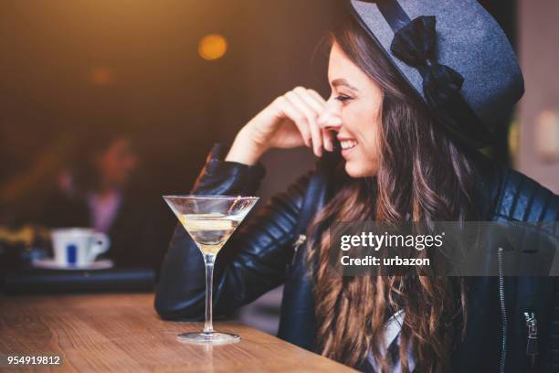 junge frau sitzt in einer bar - likör stock-fotos und bilder