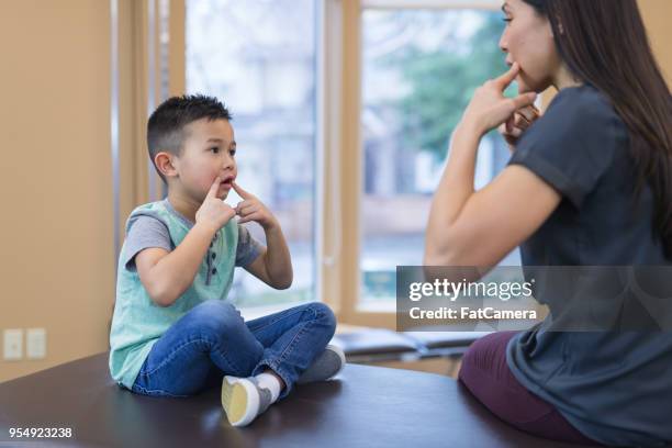 speech therapist works with a young ethnic boy - speech pathology stock pictures, royalty-free photos & images