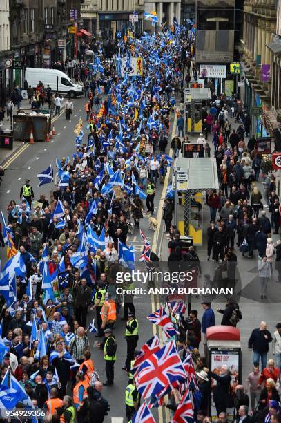 Anti-independence supporters wave Union Jack flags as thousands of demonstrators carry Saltire flags, the national flag of Scotland, as they march in...