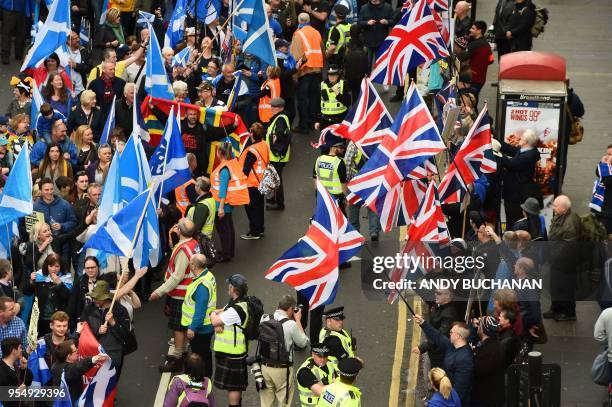 Anti-independence supporters wave Union Jack flags as thousands of demonstrators carry Saltire flags, the national flag of Scotland, as they march in...
