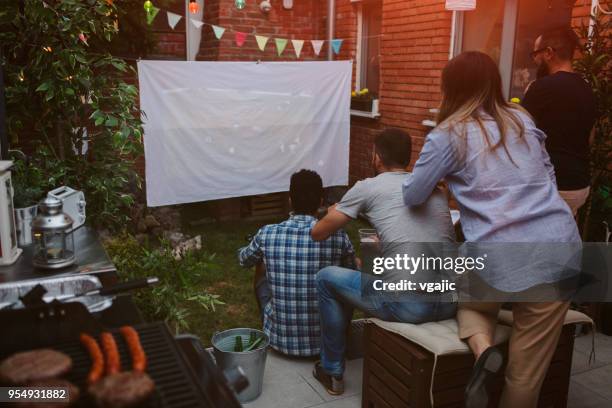 amici che guardano sport sul grande schermo nel cortile di casa - vista dalla parte posteriore di un veicolo foto e immagini stock