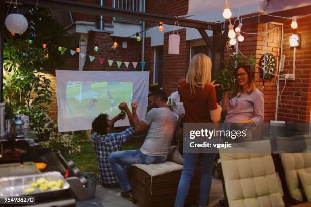 freunde, sportübertragungen auf großbildschirm im hinterhof - projektoren stock-fotos und bilder