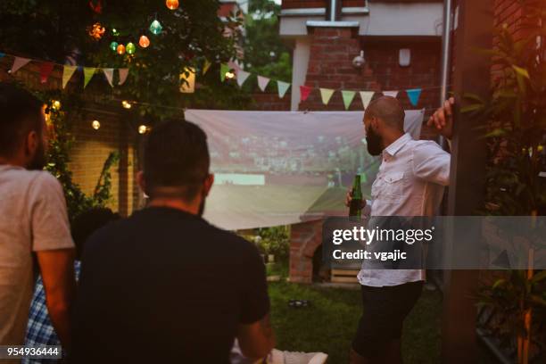 freunde, sportübertragungen auf großbildschirm im hinterhof - fussball rasen stock-fotos und bilder