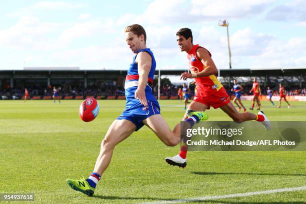 Lachie Hunter of the Bulldogs kicks the ball from Matt Rosa of the Suns during the round seven AFL match between the Western Bulldogs and the Gold...