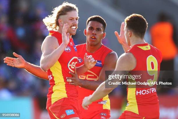 Aaron Young of the Suns Touk Miller and Ben Ainsworth of the Suns celebrates a goal during the round seven AFL match between the Western Bulldogs and...