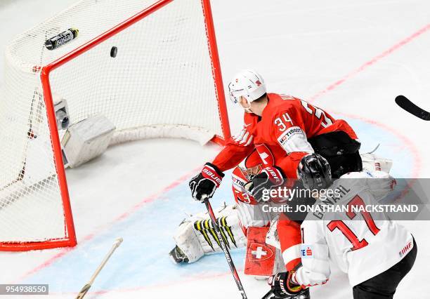 Austria's Manuel Ganahl shoots to score past Switzerland's goalie Leonardo Genoni as Switzerland's Dean Kukan looks on during the group A match...