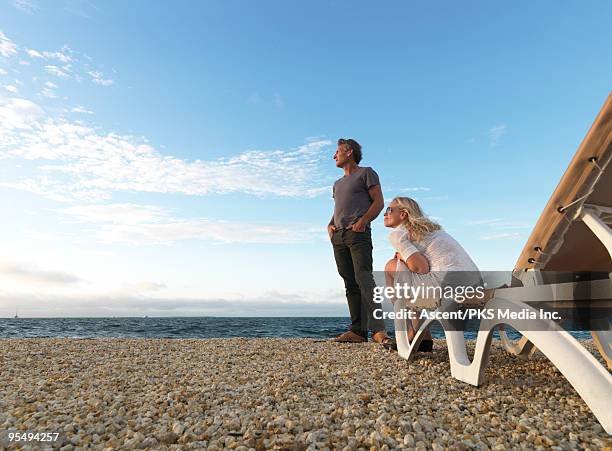 couple rest on deck chair by sea, setting sun - sun deck stock-fotos und bilder