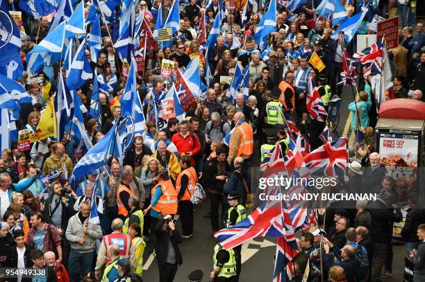 Anti-independence supporters wave Union Jack flags as thousands of demonstrators carry Saltire flags, the national flag of Scotland, as they march in...