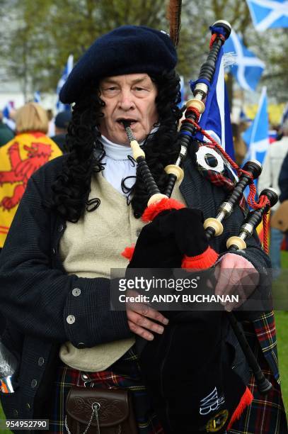 Pro-independence demonstrator with Saltire flags, the national flag of Scotland, plays the bagpipes after a march in support of Scottish...
