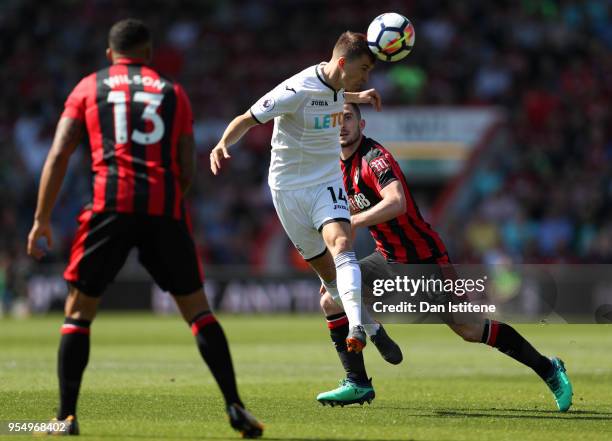 Tom Carroll of Swansea City heads the ball as Lewis Cook of AFC Bournemouth and Callum Wilson of AFC Bournemouth looks on during the Premier League...