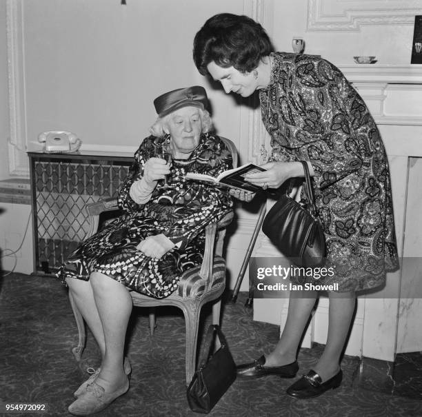 English author Dawn Langley Simmons shows a copy of her book 'Man Into Woman' to her adoptive mother, actress Dame Margaret Rutherford , during the...